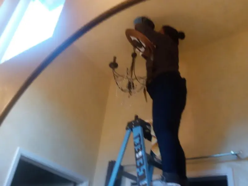 Electrician installing a chandelier in a Harrisburg residence